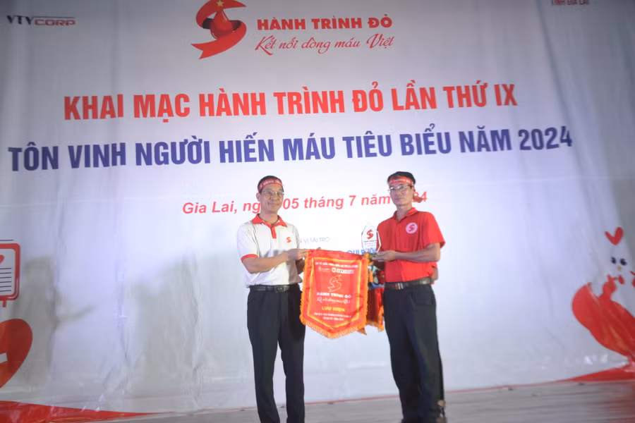 Tiến sĩ, bác sĩ Trần Ngọc Quế - Giám đốc Trung tâm máu quốc gia, Viện Huyết học Truyền máu Trung ương - Phó trưởng Ban Tổ chức Chương trình Hành trình Đỏ Trung ương năm 2024 (bên trái) tặng cờ lưu niệm Hành trình Đỏ và biểu trưng cho Ban Chỉ đạo vận động HMTN tỉnh Gia Lai. Ảnh: Hoàng Cư