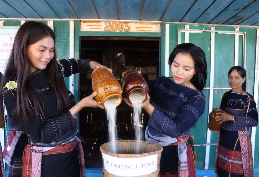 Hàng ngày nấu cơm, các chị em thôn 1 (xã Đông, huyện Kbang) bốc một nắm gạo bỏ vào hũ, sau đó đem tới nhà rông trút chung vào "Hũ gạo tình thương". Ảnh: Ngọc Minh