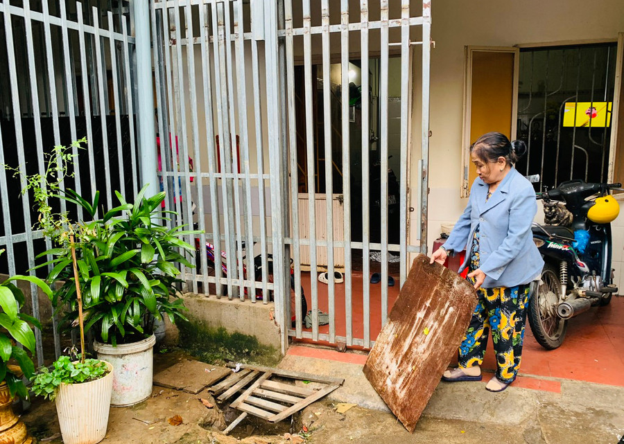 Bà Võ Thị Kim Cúc phải mở nhiều ống thoát nước trước sân và trong nhà để hạn chế nước tràn vào nhà. Ảnh: Hồng Thương