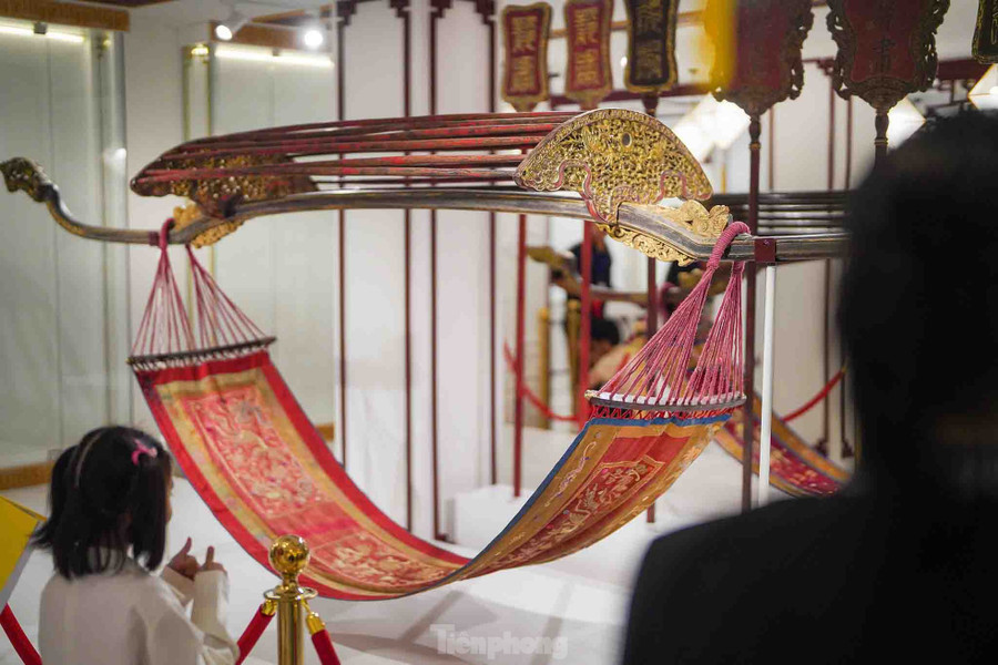 Họa tiết trang trí thân rồng, phụng được thể hiện bằng chỉ vàng, giữ được màu sắc của chất liệu theo gian. Hai chiếc võng thu hút quan khách dừng lại chiêm ngưỡng khá lâu. Họa tiết trang trí thân rồng, phụng được thể hiện bằng chỉ vàng, giữ được màu sắc của chất liệu theo gian. Hai chiếc võng thu hút quan khách dừng lại chiêm ngưỡng khá lâu.