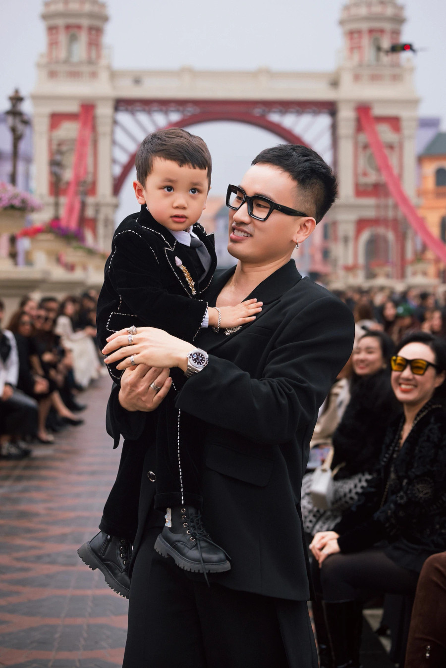 Nhà thiết kế Hà Duy dắt con trai Minh Nhật ra chào khán giả sau khi kết thúc show diễn dưới cơn mưa phùn