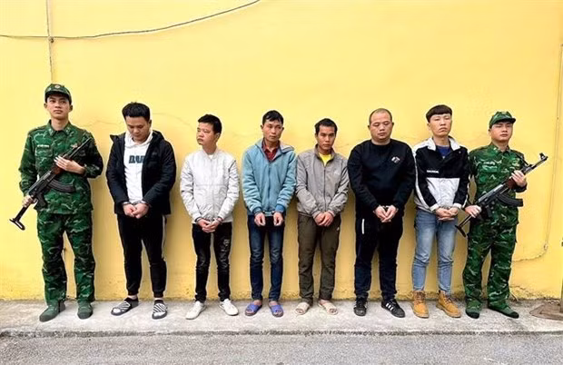 Hai đối tượng Trần Văn Binh và Dường Cắm Ngằn cầm biển đứng giữa 4 đối tượng người Trung Quốc. Ảnh: TTXVN phát