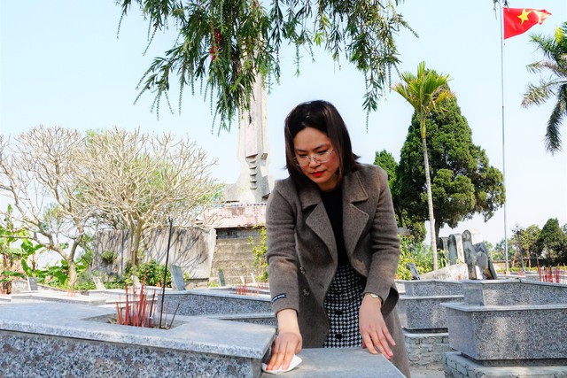 Chị Nguyễn Tú Huế bên mộ người cha Nguyễn Minh Tâm, tại nghĩa trang liệt sĩ xã Dân Chủ, H.Hưng Hà, Thái Bình. Ảnh: Mai Thanh Hải