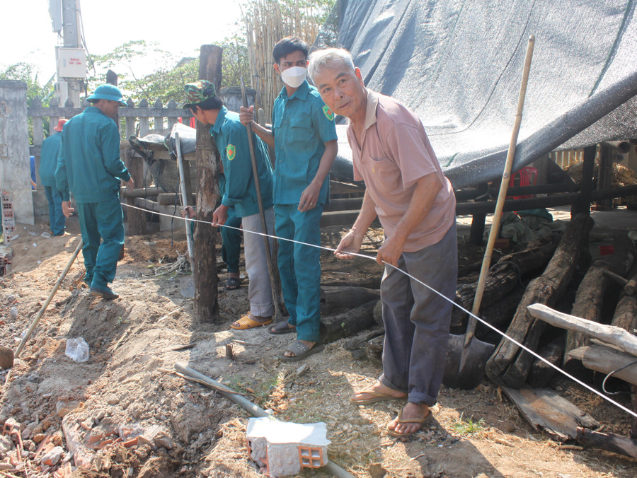 Ông Phùng Văn Sau (bìa phải) cùng lực lượng dân quân thị trấn căng dây làm lại hàng rào sau khi hiến đất làm đường. Ảnh: Vũ Chi