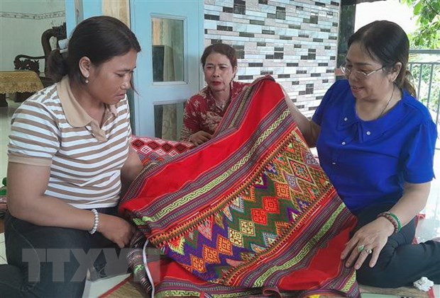 Chị Điểu Thị Ít (áo kẻ) giới thiệu sản phẩm dệt thổ cẩm cho du khách. Ảnh: K GƯỈH/TTXVN