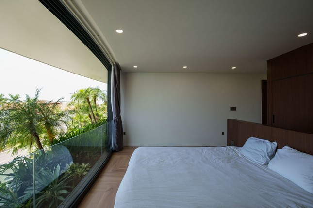 Phòng ngủ tràn ngập ánh sáng tự nhiên do sử dụng cửa kính thay cho tường bê tông. Phòng ngủ tràn ngập ánh sáng tự nhiên do sử dụng cửa kính thay cho tường bê tông.