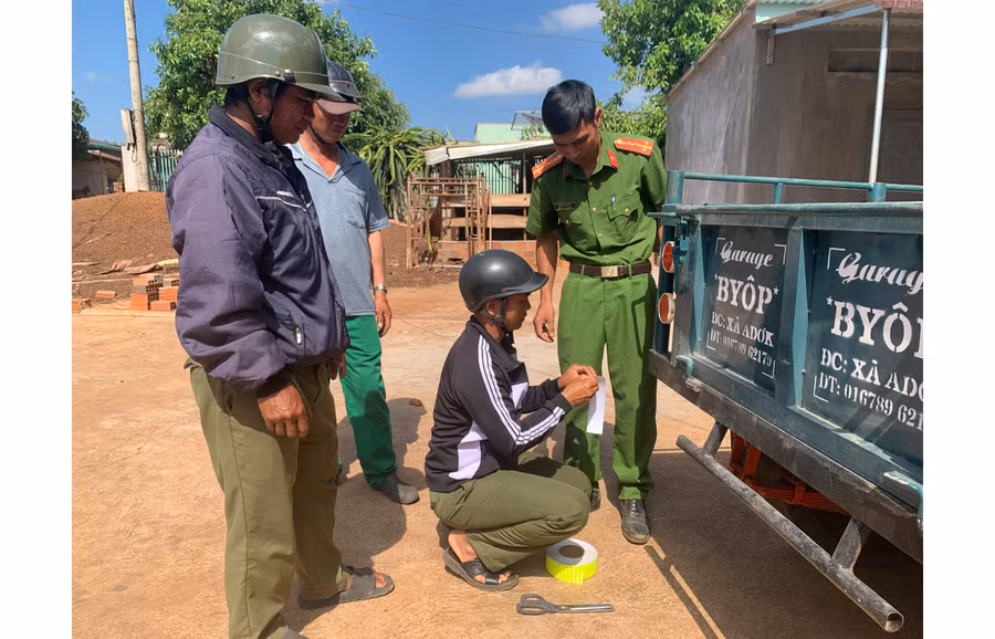 Công an xã Adơk (huyện Đak Đoa) dán phản quang miễn phí trên xe công nông của người dân. Ảnh: L.A