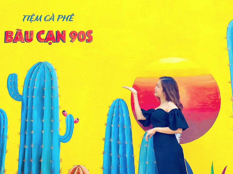 Khách chụp ảnh lưu niệm với bức tranh vẽ trên tường tại Tiệm cà phê Bàu Cạn 90S (thôn Đoàn Kết, xã Bàu Cạn, huyện Chư Prông). Ảnh: Mộc Trà