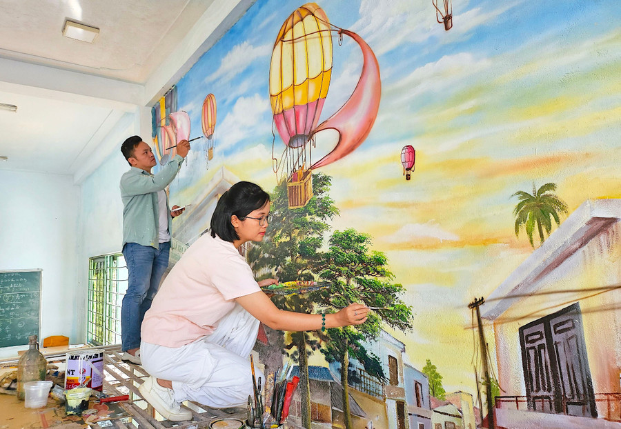 Vợ chồng anh Cao Dương-Chủ phòng vẽ Cao Dương (236/28 Phạm Văn Đồng, phường Thống Nhất, TP. Pleiku) “khoác áo mới” cho bức tường của Trung tâm Trí Việt Gia Lai. Ảnh: M.T