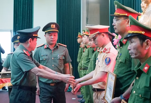 Đại tá Trần Đình Liên, Phó giám đốc Công an thành phố, trao bằng khen cho trung tá Nguyễn Đình Trung, Trạm trưởng Trạm CSGT cửa ô Hòa Nhơn