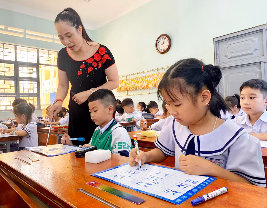 Cô Nguyễn Thị Thư-giáo viên Trường Tiểu học Nguyễn Văn Trỗi (phường Hoa Lư) hướng dẫn học sinh làm toán trên bảng con. Ảnh: Mộc Trà