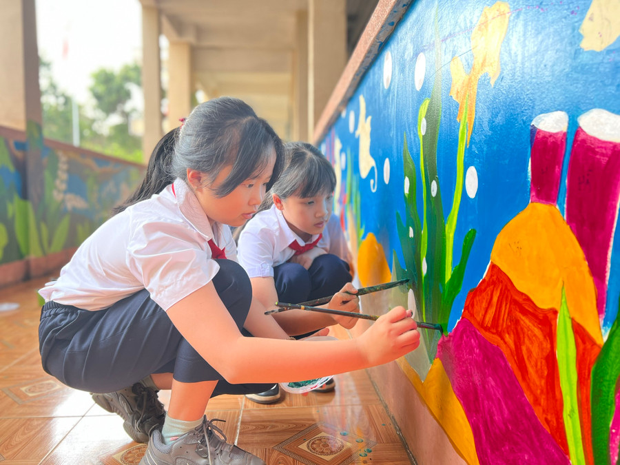 Học sinh Trường Tiểu học Nguyễn Đức Cảnh sơn vẽ hành lang trong trường. Ảnh: Phan Lài