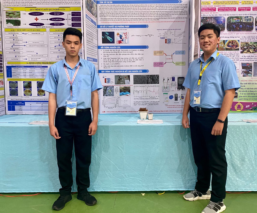 Em Văn Gia Hy (bìa phải) và em Đỗ Hà Minh Thái bên poster giới thiệu dự án của mình tại Cuộc thi khoa học kỹ thuật cấp tỉnh học sinh trung học năm học 2022-2023. Ảnh: Mộc Trà