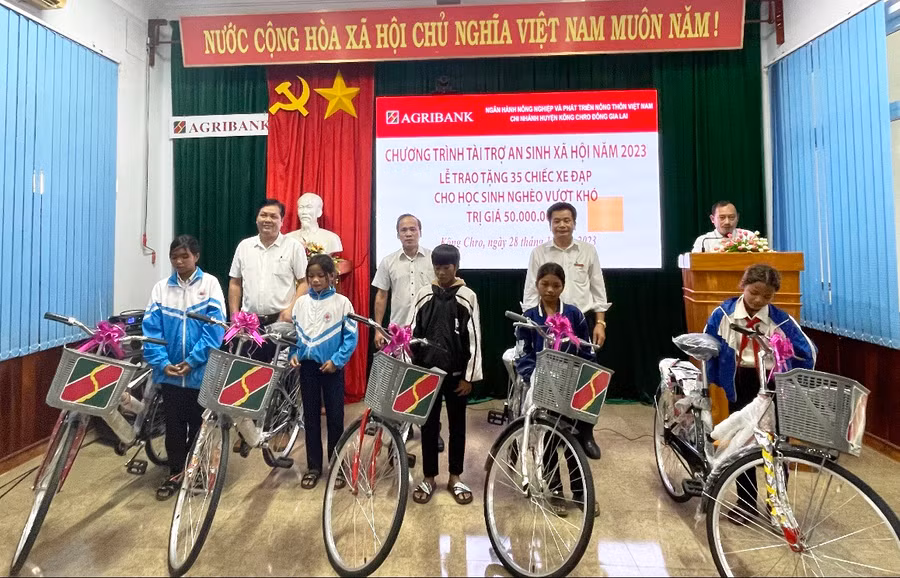 Ông Hoàng Văn Lực-Giám đốc Agribank chi nhánh Kông Chro Đông Gia Lai (bìa phải) trao tặng xe đạp cho các em học sinh. Ảnh: Phương Liên
