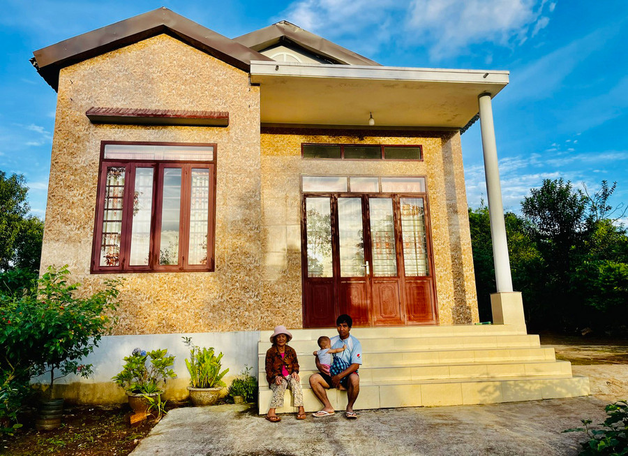 Bà Níp (làng Yam, thị trấn Ia Kha, huyện Ia Grai) cùng con cháu ngồi bên căn nhà khang trang vừa được hỗ trợ xây dựng. Ảnh: H.T