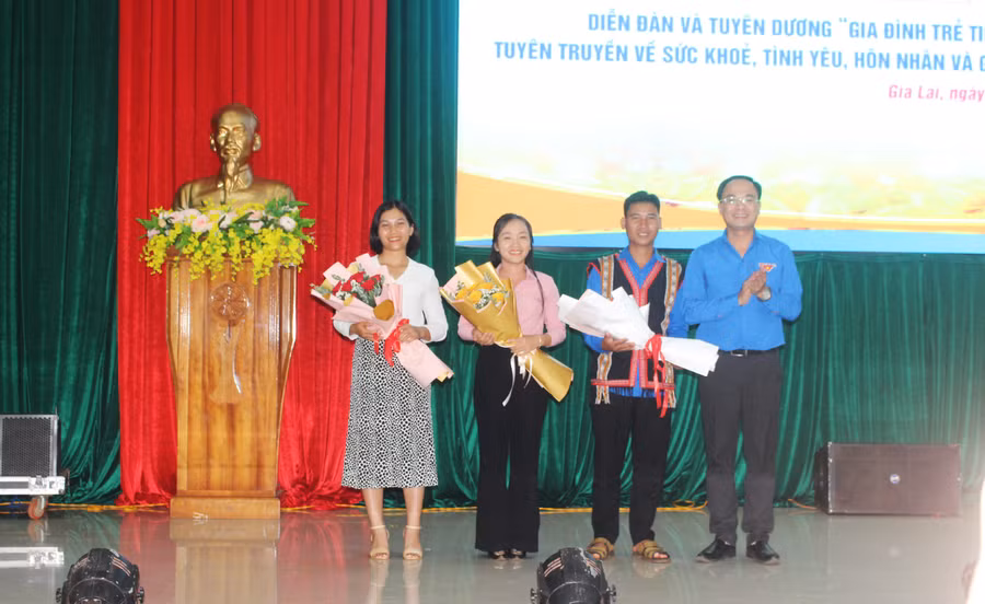 Anh Đỗ Đức Thanh (bìa phải)-Phó Bí thư Tỉnh Đoàn, Chủ tịch Hội LHTN Việt Nam tỉnh tặng hoa chúc mừng các gia đình trẻ tiêu biểu năm 2023. Ảnh: M.N