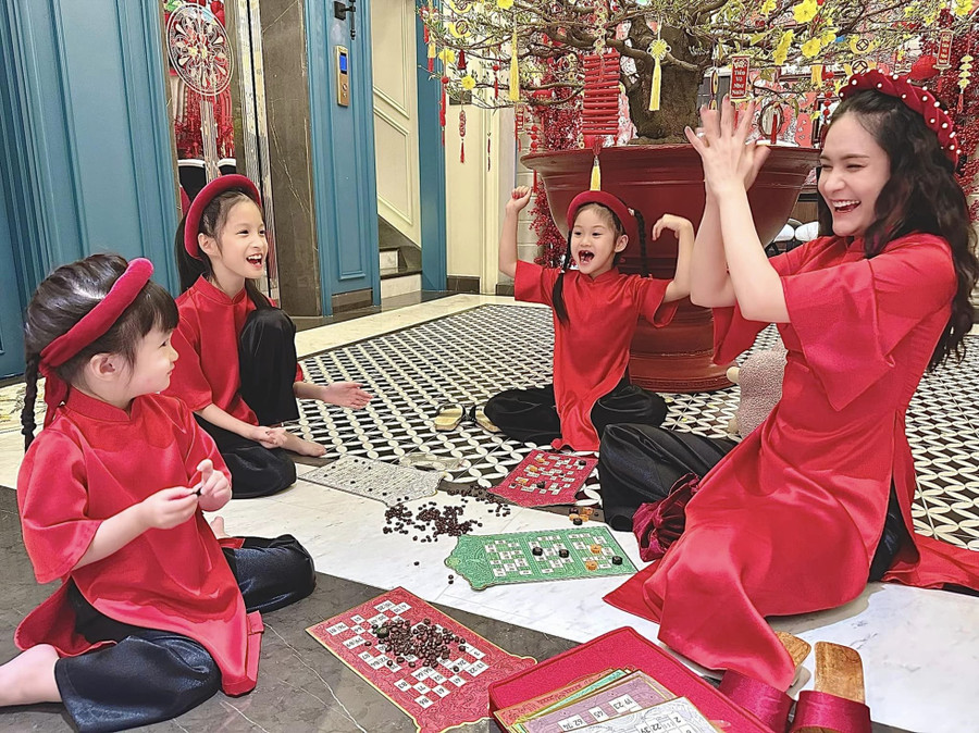 Đoàn Di Băng cùng các con diện áo dài chơi trò chơi chờ giao thừa đến: “Mấy mẹ con đang vui lắm nha. Giao thừa được đà tiến tới luôn đi“. Ảnh: Facebook nhân vật