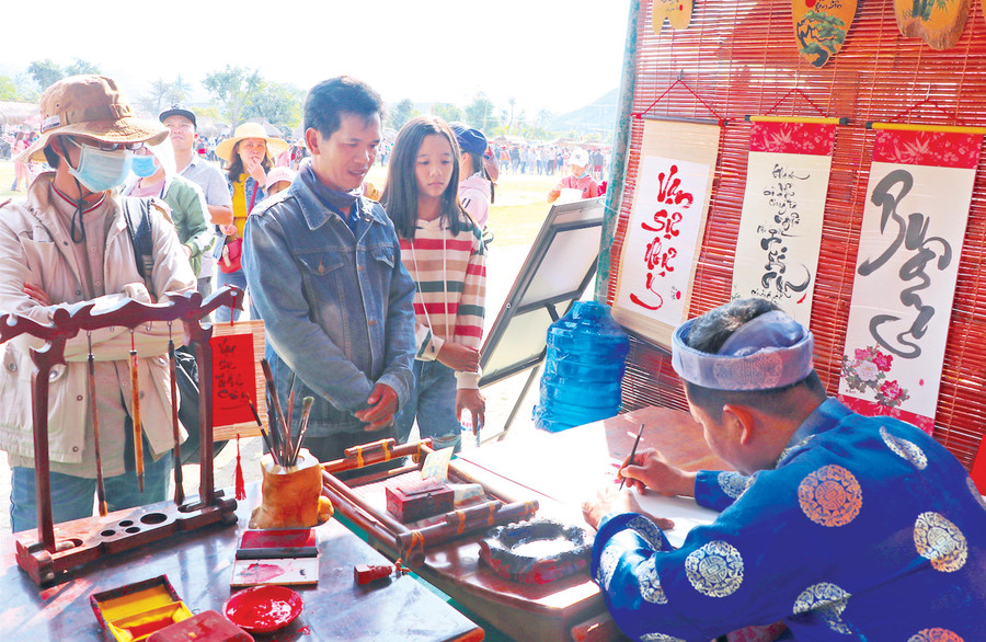 Du khách xin chữ ông đồ đầu năm tại lễ hội cầu huê. Ảnh: Ngọc Minh