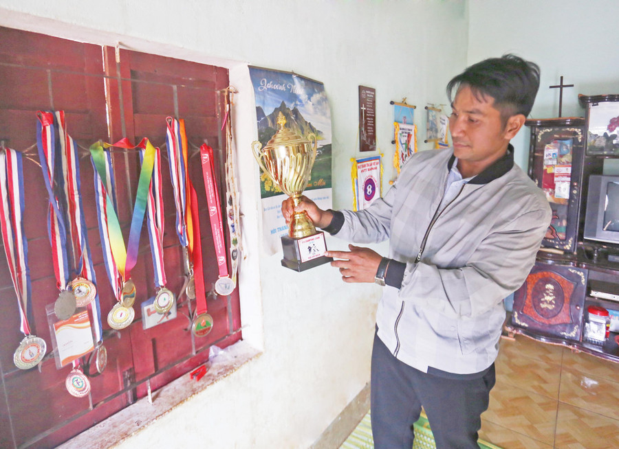Ông Khôn khoe chiếc cúp con trai giành được khi thi đấu. Ảnh: Lê Gia