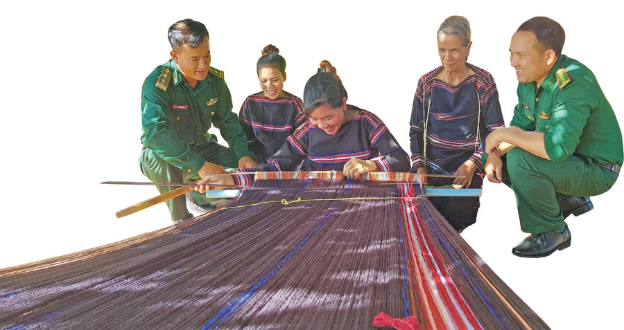 Già làng Siu Phinh (thứ 2 từ phải sang) cùng Đội Công tác địa bàn Đồn Biên phòng Ia Púch (huyện Chư Prông) vận động phụ nữ làng Goòng tham gia lớp học dệt thổ cẩm. Ảnh: Thái Kim Nga