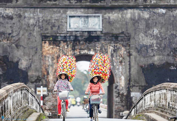 100 bông hoa giấy được cắm vào mỗi chông và người bán sẽ vác trên vai đi bán dạo khắp các phố phường, khu chợ. 100 bông hoa giấy được cắm vào mỗi chông và người bán sẽ vác trên vai đi bán dạo khắp các phố phường, khu chợ.