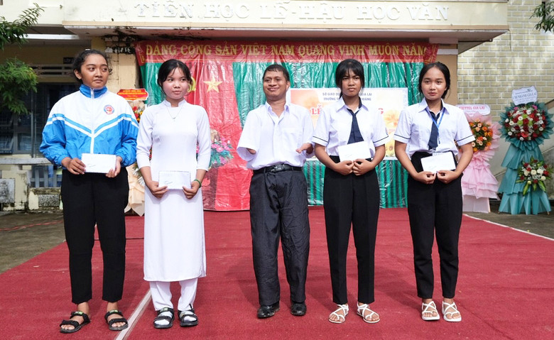 Anh Nay Djruêng (ở giữa)-cựu học sinh của Trường THPT Đinh Tiên Hoàng trao học bổng "Đi qua mùa rẫy" cho học sinh hiếu học. Ảnh: Hoàng Ngọc Anh Nay Djruêng (ở giữa)-cựu học sinh của Trường THPT Đinh Tiên Hoàng trao học bổng "Đi qua mùa rẫy" cho học sinh hiếu học. Ảnh: Hoàng Ngọc