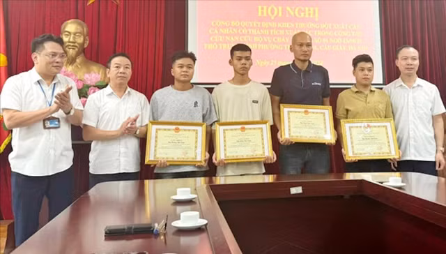 Anh Đồng Văn Tuấn (thứ 3 từ trái qua) và anh Hoàng Anh Tuấn (giữa), người hùng cùng lực lượng cứu hộ cứu người trong vụ cháy nhà nằm trong ngõ 43 Trung Kính, nhận giấy khen của UBND quận Cầu Giấy, TP Hà Nội. Ảnh: HOÀNG PHONG