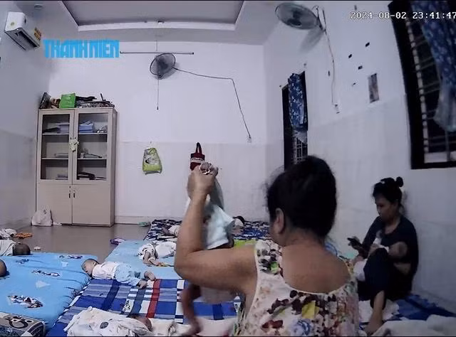 Em bé (khoảng 1 tháng tuổi) da còn đỏ hỏn bị bà Tuyền xách tay nhấc bổng trong lúc thay khăn