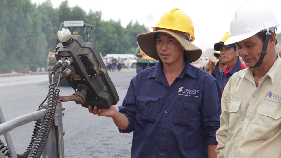 Những công nhân kỹ thuật miệt mài trực bên máy rải nhựa Những công nhân kỹ thuật miệt mài trực bên máy rải nhựa