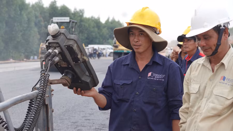 Những công nhân kỹ thuật miệt mài trực bên máy rải nhựa