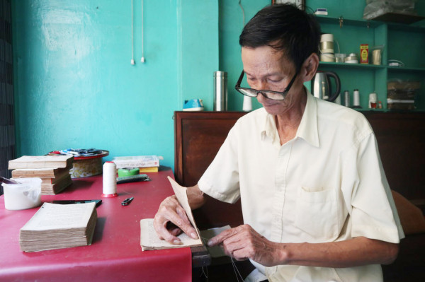 Ông Võ Văn Rạng tỉ mẩn sửa chữa từng trang sách cũ.