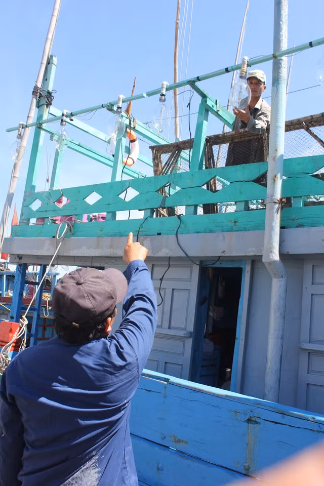 Ngư dân Trần Cu Anh và ngư dân Lê Tấn Thành kiểm tra giàn đèn trên tàu trước giờ xuất phát