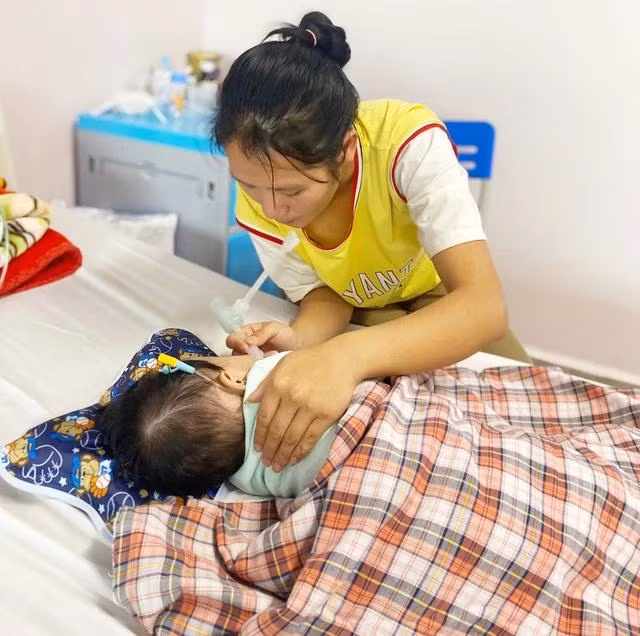 Chị Lý Thị Cu hút đờm cho con khi bé liên tục bị khó thở, gồng cứng người