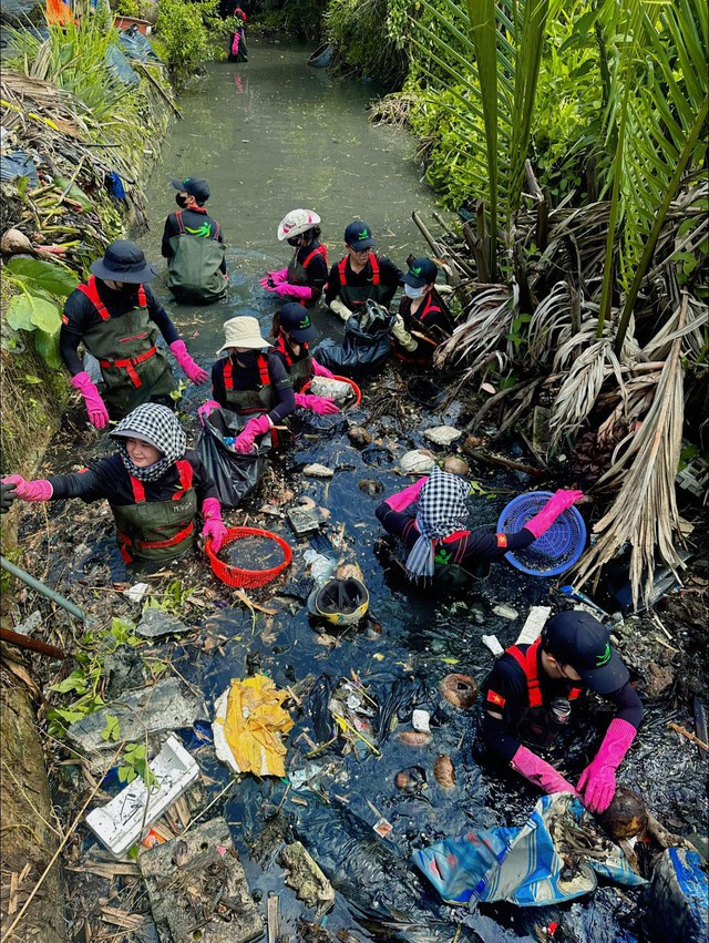 Các thành viên Sài Gòn Xanh dầm mình dọn rác ở một dòng kênh. (Ảnh do nhân vật cung cấp)
