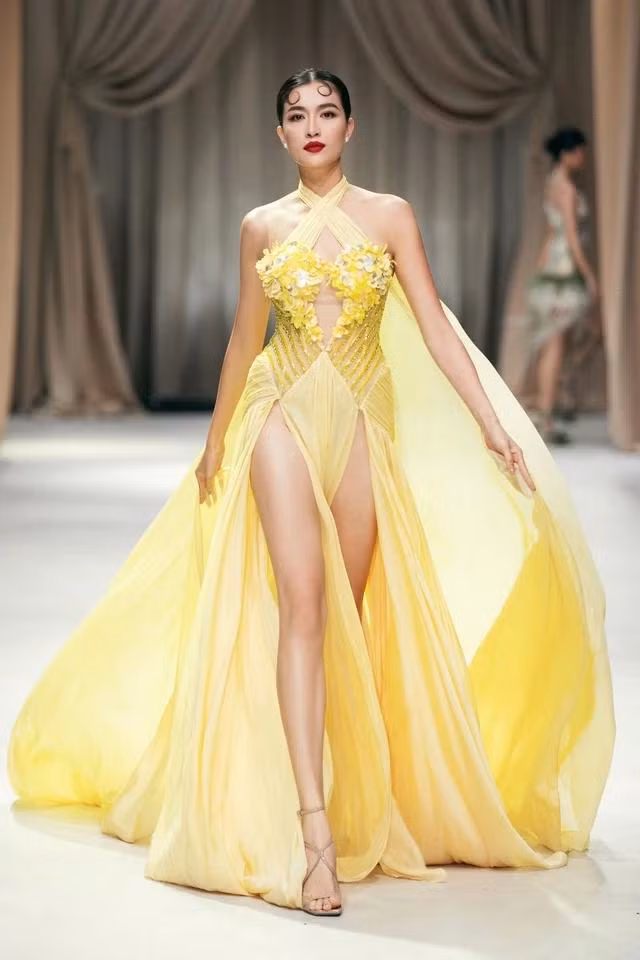 Á hậu Lệ Hằng trình diễn mẫu đầm dạ hội màu vàng với các chi tiết đan lát, thêu đính cầu kỳ tạo nên cái nhìn hài hòa của thời trang hiện đại và nét đẹp truyền thống