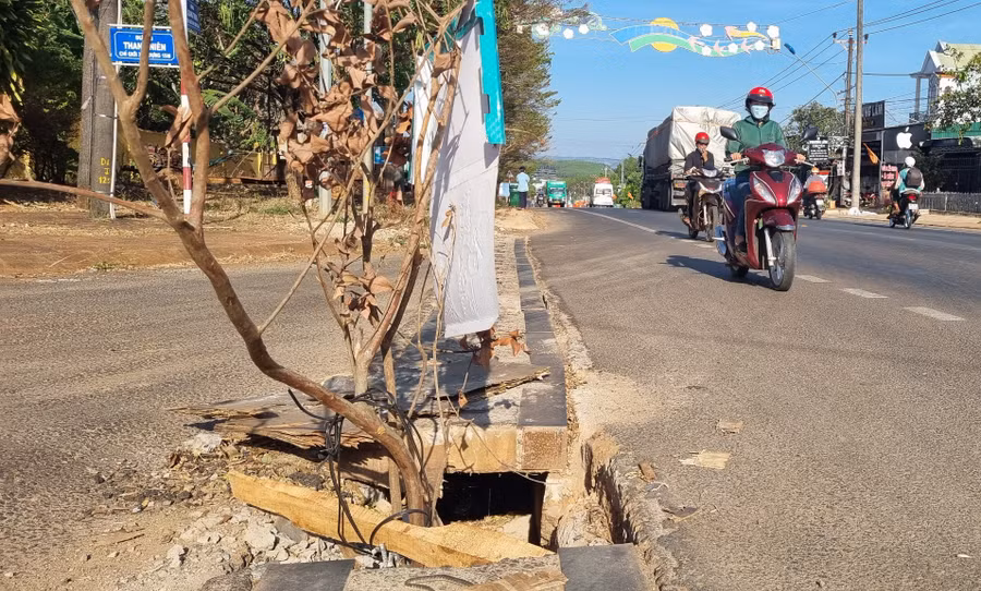 Người dân dùng vật dụng che chắn cảnh báo nguy hiểm để người đi đường né tránh nắp cống nước bị vỡ. Ảnh: K.P