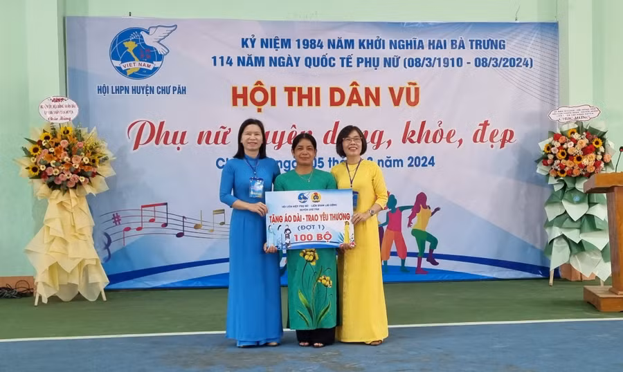 Bà Nguyễn Thị Bảy-Chủ tịch Hội LHPN huyện Chư Păh (bìa phải) trao 100 bộ áo dài truyền thống cho hội viên phụ nữ. Ảnh: H.P