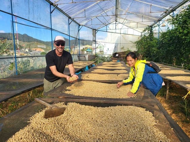 Vợ chồng Rolan đảo cà phê ở giàn phơi. Ảnh: Gia Bình