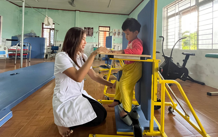 Chị Kpă H'Ơi giúp cháu Tạ Thị Kim Ngân tập vật lý trị liệu, phát triển vận động. Ảnh: P.L Chị Kpă H'Ơi giúp cháu Tạ Thị Kim Ngân tập vật lý trị liệu, phát triển vận động. Ảnh: P.L