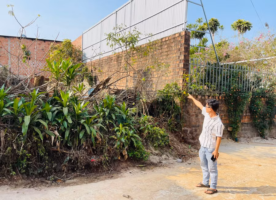 Anh Hồ Thanh Thuận (tổ 3, phường Hội Phú, TP. Pleiku) chỉ tay về khu vực chứa chất thải chăn nuôi của ông Lê Văn Tự ở sát ngay tường rào nhà mình. Ảnh: N.H