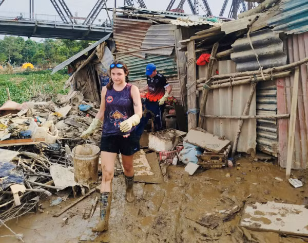 Tình nguyện viên nước ngoài hỗ trợ người dân tìm kiếm những gì còn sót lại sau bão lũ.