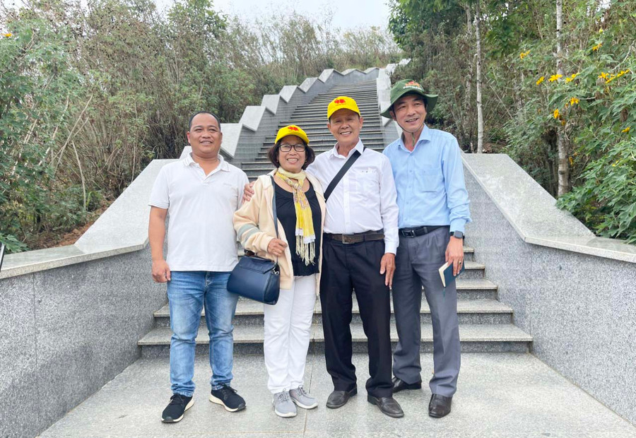 Tác giả (bìa phải) chụp ảnh lưu niệm cùng du khách tham quan tại cột mốc. Ảnh: D.L