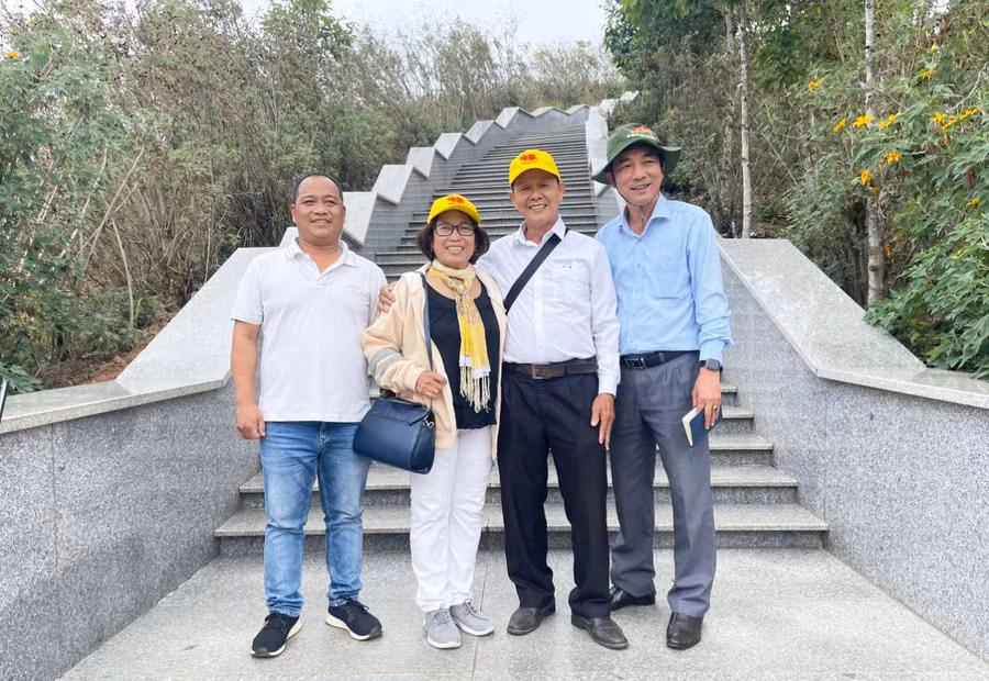 Tác giả (bìa phải) chụp ảnh lưu niệm cùng du khách tham quan tại cột mốc. Ảnh: D.L