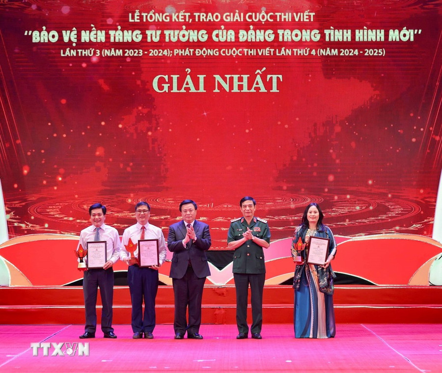 Đại tướng Phan Văn Giang, Ủy viên Bộ Chính trị, Bộ trưởng Bộ Quốc phòng và đồng chí Nguyễn Xuân Thắng, Ủy viên Bộ Chính trị, Chủ tịch Hội đồng Lý luận Trung ương, Giám đốc Học viện Chính trị Quốc gia Hồ Chí Minh trao giải cho các tác giả, nhóm tác giả đoạt giải Nhất. (Ảnh: Thanh Tùng/TTXVN)