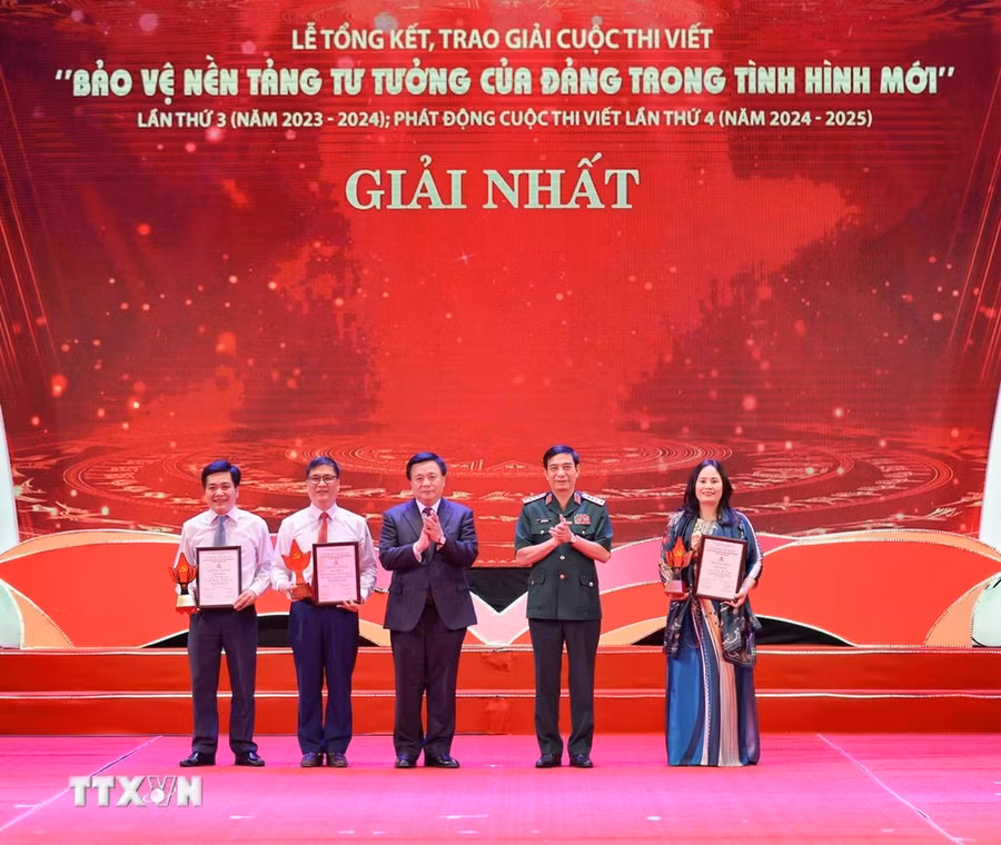 Đại tướng Phan Văn Giang, Ủy viên Bộ Chính trị, Bộ trưởng Bộ Quốc phòng và đồng chí Nguyễn Xuân Thắng, Ủy viên Bộ Chính trị, Chủ tịch Hội đồng Lý luận Trung ương, Giám đốc Học viện Chính trị Quốc gia Hồ Chí Minh trao giải cho các tác giả, nhóm tác giả đoạt giải Nhất. (Ảnh: Thanh Tùng/TTXVN)