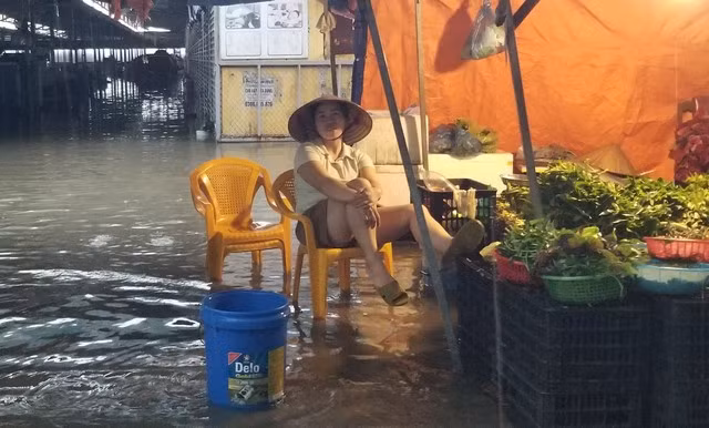 Tiểu thương chợ dân sinh Đông Hải 2 (Q.Hải An) ngồi gác chân lên cho khỏi nước, ngóng chờ người mua