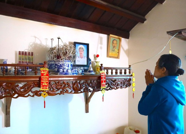Bà Thanh thắp hương lên bàn thờ con trai liệt sĩ. Bà Thanh thắp hương lên bàn thờ con trai liệt sĩ.