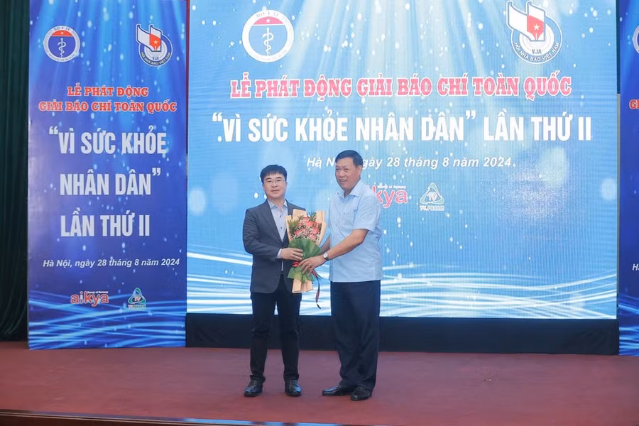 Thứ trưởng Bộ Y tế Đỗ Xuân Tuyên tặng hoa ông Hà Ngọc Sơn - đơn vị đồng hành chính cùng Giải báo chí toàn quốc Vì sức khỏe nhân dân. (Ảnh: Minh Quyết/Vietnam+)