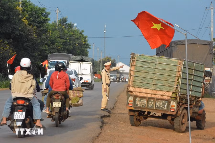 Lực lượng cảnh sát giao thông phân luồng cho xe chở sầu riêng để giảm áp lực lưu thông trên Quốc lộ 26. (Ảnh: Tuấn Anh/TTXVN)