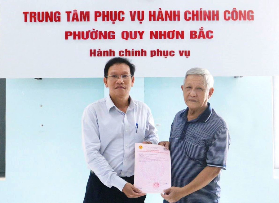 Đại diện lãnh đạo UBND phường Quy Nhơn Bắc trao giấy chứng nhận quyền sử dụng đất đầu tiên cho 1 hộ dân tại địa phương sau khi vận hành mô hình chính quyền địa phương 2 cấp. Ảnh: Nguyễn Nguyệt 92.jpg
